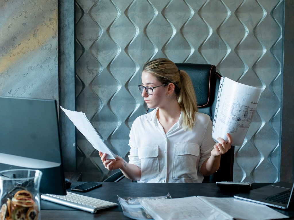 portrait-young-office-worker-woman-sitting-office-desk-with-documents-looking-them-with-serious-confident-expression-face-working-office.png